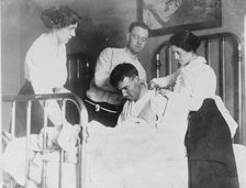 Dr. James F Grant, ship's surgeon, fixing up Gordan G Davidson, survivor of EMPRESS OF..., 1914. Creator: Bain News Service
