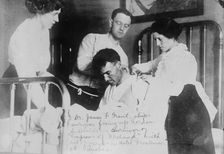 Dr. James F. Grant, ship's surgeon, fixing up Gordon G. Davidson, survivor of EMPRESS OF..., 1914. Creator: Bain News Service