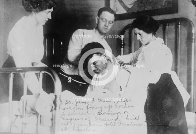 Dr. James F. Grant, ship's surgeon, fixing up Gordon G. Davidson, survivor of EMPRESS OF..., 1914. Creator: Bain News Service.