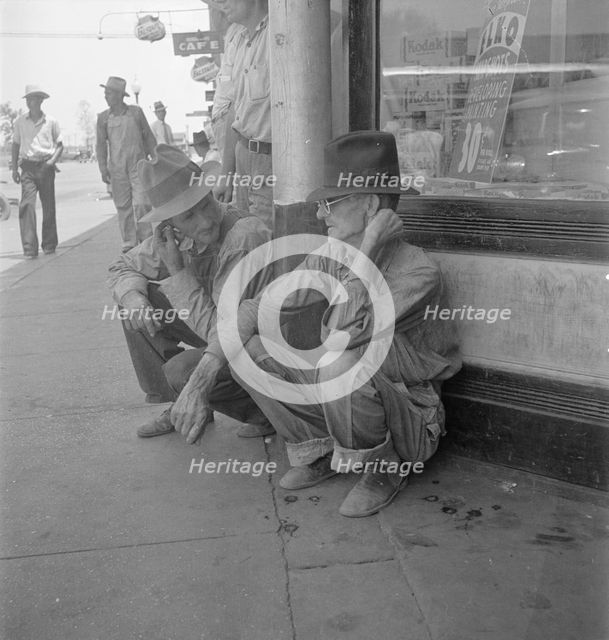 Drought farmers line the shady side of the main street of the town, Sallisaw, Oklahoma, 1936. Creator: Dorothea Lange.