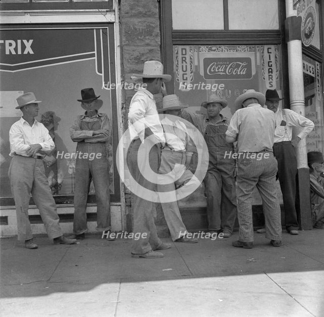 Drought farmers line the shady side of the main street of the town, Sallisaw, Oklahoma, 1936. Creator: Dorothea Lange.
