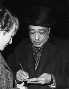 Duke Ellington signing his autograph, c1962. Creator: Brian Foskett