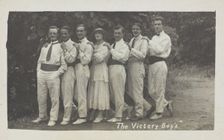 Entertainers, one in drag, pose in a line in front of foliage, [between 1910 and 1919?]. Creator: Unknown