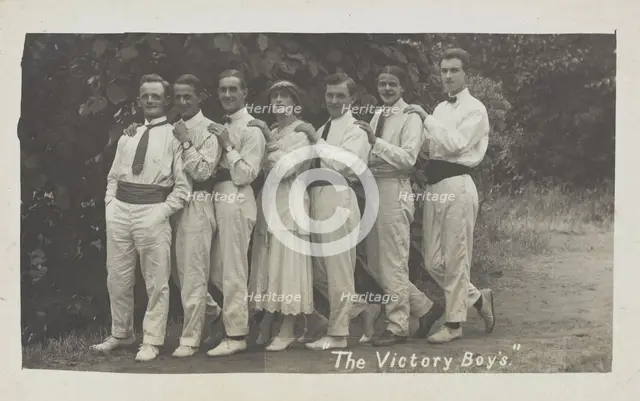 Entertainers, one in drag, pose in a line in front of foliage, [between 1910 and 1919?]. Creator: Unknown.