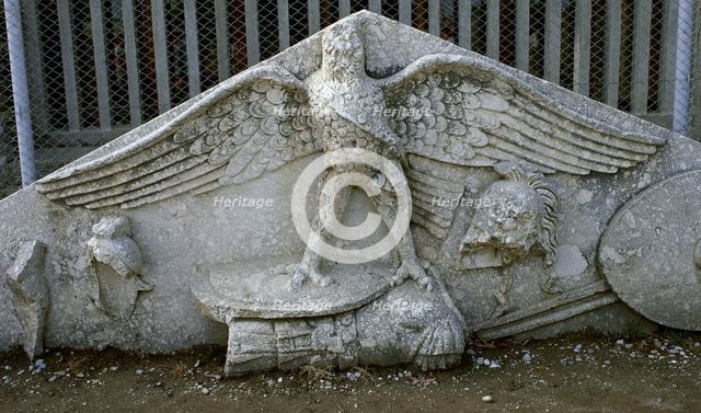 Eagle figure, armour, spear, helmet and circular shield, Roman gable, Side, Turkey, 1999. Creator: LTL.