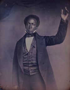 Edward J. Roye, three-quarter length portrait, standing, with hand raised, between 1856 and 1858. Creator: Augustus Washington