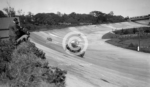 Eddie Hall's Bentley leading a Bugatti on the banking at Brooklands.   Artist: Bill Brunell.