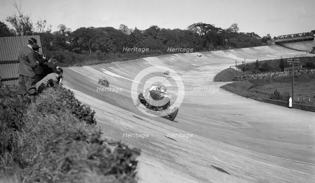 Eddie Hall's Bentley leading a Bugatti on the banking at Brooklands.   Artist: Bill Brunell.