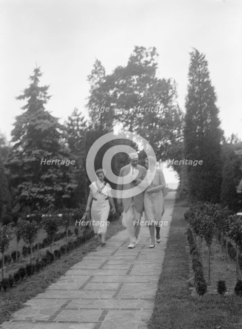 Edge, Charles N., walking with Margaret Edge and another woman in his garden, 1932 or 1933. Creator: Arnold Genthe.