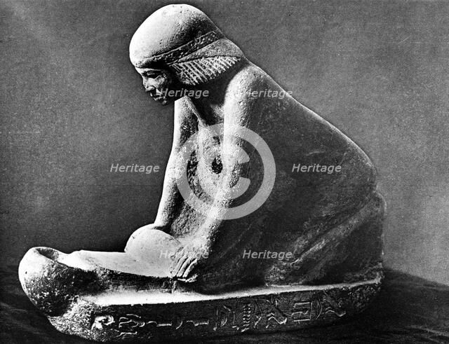 Egyptian tomb figure of a woman grinding corn using a saddle quern, c2500 BC. Artist: Unknown
