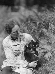Egger, Gabrielle, Miss, friend of, with cat, seated outdoors, between 1926 and 1930. Creator: Arnold Genthe