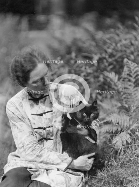 Egger, Gabrielle, Miss, friend of, with cat, seated outdoors, between 1926 and 1930. Creator: Arnold Genthe.