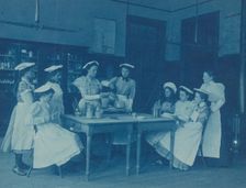 Eight teenage girls wearing aprons and chef caps learning to cook...Washington DC high school, 1899? Creator: Frances Benjamin Johnston