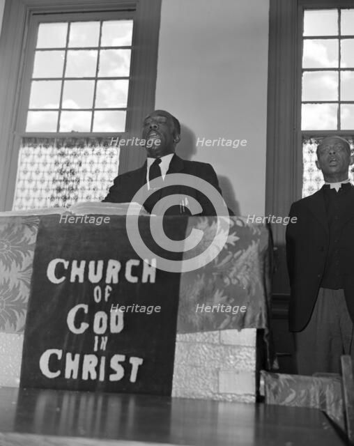 Elder Kelsey, pastor of the Church of God in Christ, opening a service..., Washington, D.C., 1942. Creator: Gordon Parks.
