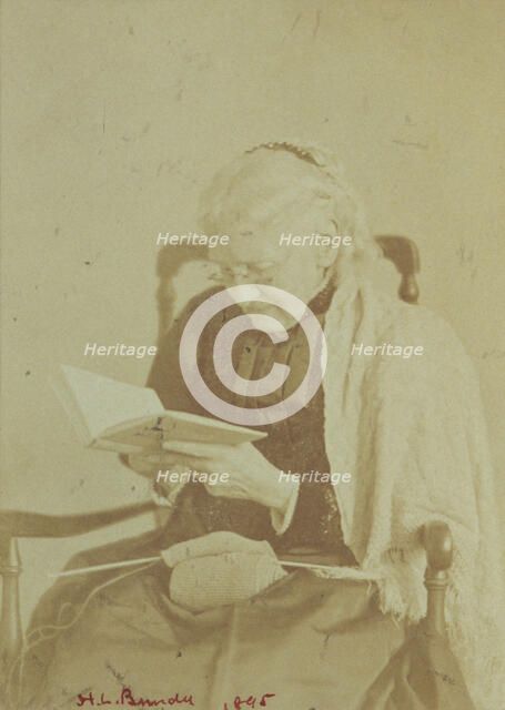 Elderly woman seated and reading a book with knitting in her lap, 1895. Creator: Horace L Bundy.