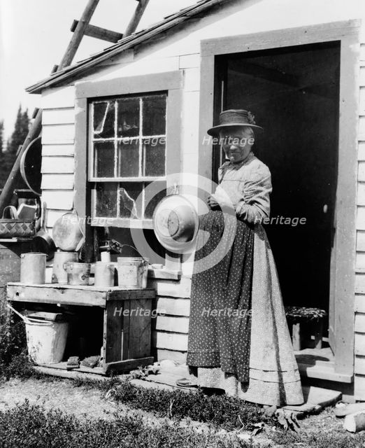 Elderly woman, standing at doorway, on Mackinac Island, Michigan, 1903. Creator: Frances Benjamin Johnston.