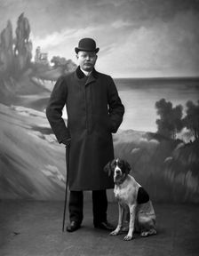 Elegant man wearing a black overcoat posing with his dog, Landskrona, Sweden, 1910. Creator: Unknown