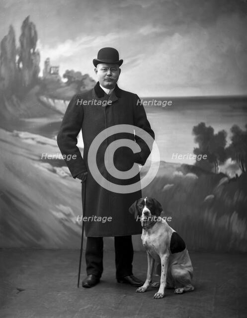 Elegant man wearing a black overcoat posing with his dog, Landskrona, Sweden, 1910. Artist: Unknown