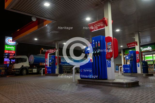 Esso petrol station forecourt with tanker delivering fuel, 2020. Creator: Tim Woodcock.