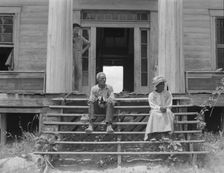 Ex-slave and wife on steps of plantation house now in decay, Greene County, Georgia, 1937. Creator: Dorothea Lange