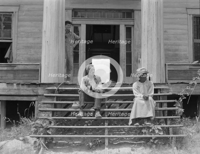 Ex-slave and wife on steps of plantation house now in decay, Greene County, Georgia, 1937. Creator: Dorothea Lange.