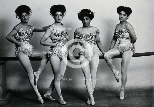 Four young woman acrobats (?), posing on a bar in a photographic studio, between 1899 and 1908. Creator: Unknown.