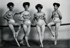 Four young woman acrobats (?), posing on a bar in a photographic studio, between 1899 and 1908. Creator: Unknown