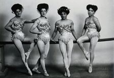 Four young woman acrobats (?), posing on a bar in a photographic studio, between 1899 and 1908. Creator: Unknown