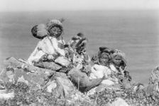 Four Eskimo children, at edge of cliff, in holiday costume, Nunivak, Alaska, c1929. Creator: Edward Sheriff Curtis