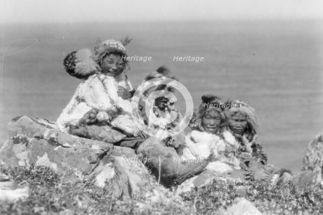 Four Eskimo children, at edge of cliff, in holiday costume, Nunivak, Alaska, c1929. Creator: Edward Sheriff Curtis.