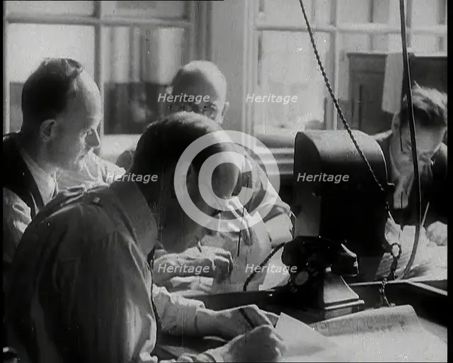 Four Male British Journalists Sitting Around a Table Covered in Papers and Writing, 1939. Creator: British Pathe Ltd.