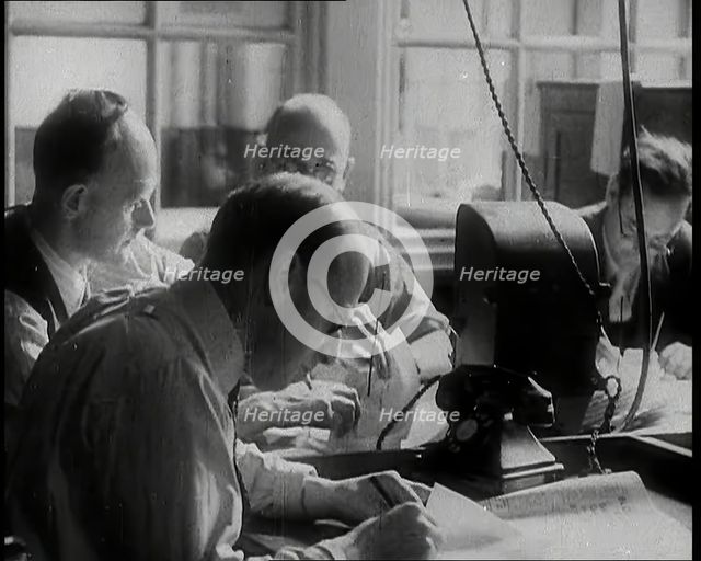Four Male British Journalists Sitting Around a Table Covered in Papers and Writing, 1939. Creator: British Pathe Ltd.