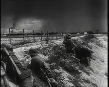 Four Male German Army Soldiers Lying Low on a Slope Below a Fence While Columns of Smoke..., 1939. Creator: British Pathe Ltd
