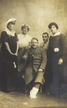 Four soldiers posing, three in drag, with an injured soldier seated in the centre, [1910-1919?]. Creator: Unknown