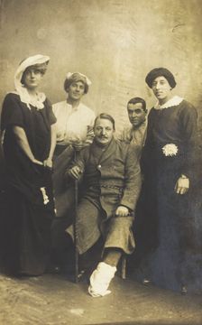 Four soldiers posing, three in drag, with an injured soldier seated in the centre, [1910-1919?]. Creator: Unknown