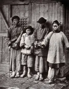 Foochow, China: four people with leprosy, wearing thick clothing, standing outside a wooden..., 1873 Creator: John Thomson