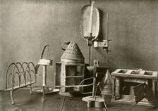 Foot-warmer; oil lamps; candle sconce; tin lantern; and toaster c18th century, (1937). Creator: Unknown