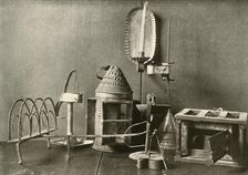 Foot-warmer; oil lamps; candle sconce; tin lantern; and toaster c18th century, (1937). Creator: Unknown