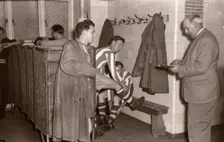 Footballers adjust their boots in the locker room, 1953