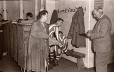 Footballers adjust their boots in the locker room, 1953