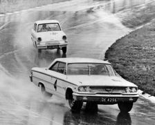 Ford Galaxie, J.Sears, leads Ford Anglia in wet at Brands Hatch 1963. Creator: Unknown