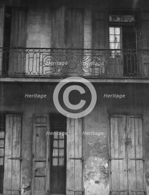Facade of a building with shuttered doors and balcony, New Orleans or Charleston..., c1920-1926. Creator: Arnold Genthe.