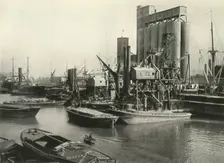 "Factories, Refineries, Granaries Grow Thick" Ship Discharging Grain by Floating Pneumatic... 1937 Creator: J Dixon-Scott
