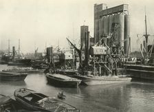 "Factories, Refineries, Granaries Grow Thick" Ship Discharging Grain by Floating Pneumatic... 1937 Creator: J Dixon-Scott
