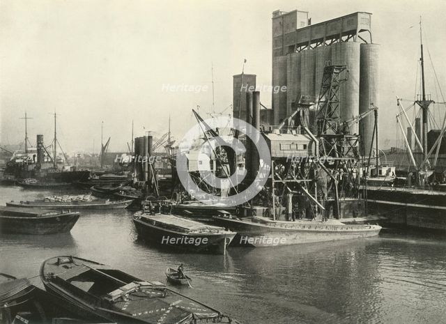 "Factories, Refineries, Granaries Grow Thick" Ship Discharging Grain by Floating Pneumatic...', 1937 Creator: J Dixon-Scott.