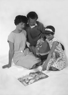 Family group looking at a magazine, 1963. Artist: Michael Walters