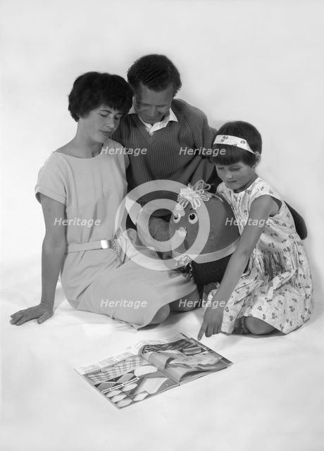 Family group looking at a magazine, 1963. Creator: Michael Walters.