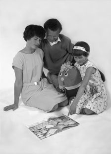 Family group looking at a magazine, 1963. Creator: Michael Walters