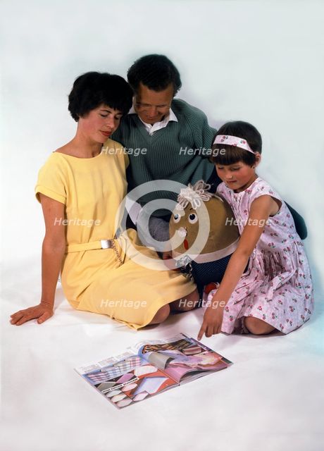 Family group looking at a magazine, 1963. Creator: Michael Walters.