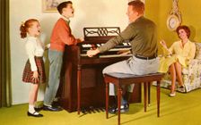 Family singing around a Wurlitizer organ as father plays, De Kalb, Illinois, USA, 1962